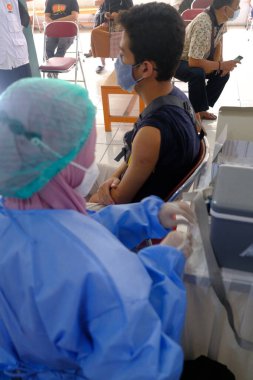 Yogya, Endonezya - 2 Eylül 2021: Yogyakarta 'da Covid-19 aşısı. Doktor aşıyı hastaya enjekte ediyor. - Ne? Bu aşı yaşlı, sağlıklı ve genç grupları hedef almaktadır..