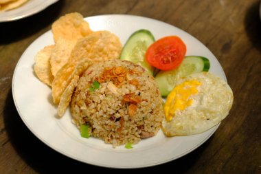 Nasi Goreng Telur Mata Sapi. Kızarmış pirinç, sarımsak, arpacık soğanı, biber, tuz ve karides ezmesiyle kızartılmış beyaz pirinçtir. Kızarmış yumurta, domates, salatalık dilimleri ve krakerlerle servis edilir. Endonezya yemekleri.