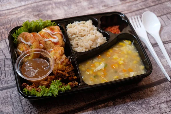 Stock image healthy food bento with brown rice, omelette, vegetable corn soup, tempeh and fruit jelly. For diet weight loss program. healthy lunch menu in a plastic container. catering menu diet.