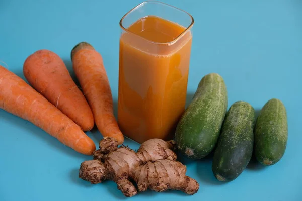 Havuç, salatalık ve zencefil suyu meyve sıkacağında işlenmiş. Temiz bir bardakta servis edilen taze sebze suyu..