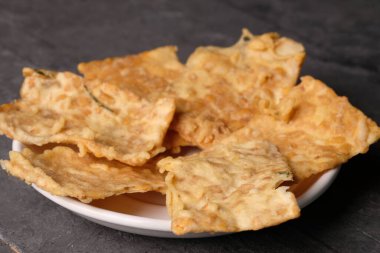 Keripik Tempe. Tempeh Chips ince dilimlenmiş Tempeh 'den yapılan tipik bir Endonezya aperatifi sonra pirinç unu, hindistan cevizi sütü ve baharatlarla kızartılır. Endonezya yemeği. Beyaz seramik tabakta servis ediliyor. Kripik.