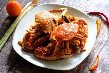 Rajungan Asam Manis, yengeç kıyı bölgesinde popüler bir deniz ürünleri tabağıdır. Yengeç, domates sosu, biber, limon otu, marul ve baharatla servis edilir. Tahta masada servis edilmiş. Endonezya yemekleri.