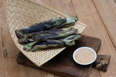 Otak-otak tengiri bakar, muz yapraklarına sarılmış uskumru balığıyla işlenmiş, sonra da kömürde kızartılıyor. Fıstık sosu. Endonezya yemekleri.