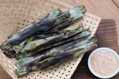 Otak-otak tengiri bakar, muz yapraklarına sarılmış uskumru balığıyla işlenmiş, sonra da kömürde kızartılıyor. Fıstık sosu. Endonezya yemekleri.
