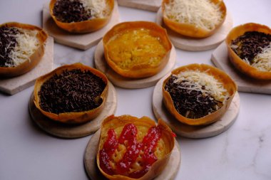 Martabak Manis. Tatlı Martabak. Un, yumurta, vanilya, üzerine rendelenmiş peynir, çikolata, reçel ve ananas, çilek reçeli. Soğutma rafında servis edilmiş. Endonezya yemekleri.
