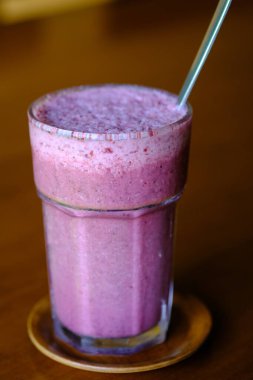 Kırmızı ejderha meyveli smoothie. Kırmızı ejderha meyve suyu. C vitamini ve antioksidan içeren ejderha meyvesinden yapılmış sağlıklı bir içecek. Sağlığa yararlı olan diyet içecekleri. Beyaz ahşap masada servis edilir..