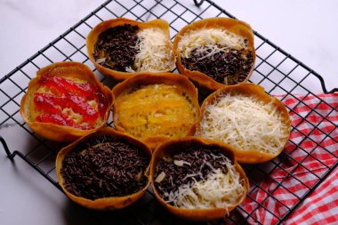 Martabak Manis. Tatlı Martabak. Un, yumurta, vanilya, üzerine rendelenmiş peynir, çikolata, reçel ve ananas, çilek reçeli. Soğutma rafında servis edilmiş. Endonezya yemekleri.