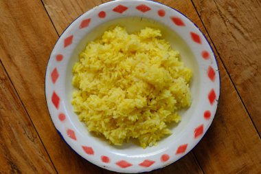 Nasi Kuning, zerdeçal, pirinç, hindistan cevizi sütü ve baharattan yapılmış Endonezya sarısı pilavıdır. Eski bir tabakta. Endonezya yemekleri.