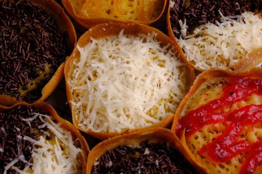Martabak Manis. Tatlı Martabak. Un, yumurta, vanilya, üzerine rendelenmiş peynir, çikolata, reçel ve ananas, çilek reçeli. Soğutma rafında servis edilmiş. Endonezya yemekleri.