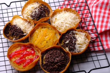 Martabak Manis. Tatlı Martabak. Un, yumurta, vanilya, üzerine rendelenmiş peynir, çikolata, reçel ve ananas, çilek reçeli. Soğutma rafında servis edilmiş. Endonezya yemekleri.
