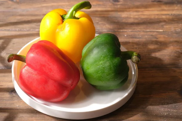 three red, green, yellow peppers on a brown rustic wooden table. Peppers can be used as raw material for salads and cooking. paprika merah, hijau, kuning.