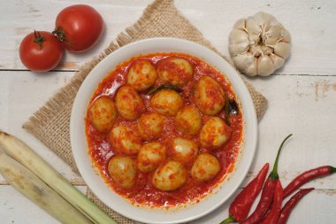 Telur Balado Tomatı ya da geleneksel Endonezya usulü yumurta, haşlanmış yumurta, domates ve biber ezmesi ya da sambal ile yapılan geleneksel Endonezya yemeği, ahşap masadaki toprak tabağında servis edilir. Sarımsak, domates, biber..