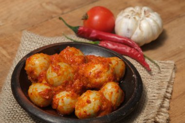 Telur Balado Tomatı ya da geleneksel Endonezya usulü yumurta, haşlanmış yumurta, domates ve biber ezmesi ya da sambal ile yapılan geleneksel Endonezya yemeği, ahşap masadaki toprak tabağında servis edilir. Sarımsak, domates, biber..