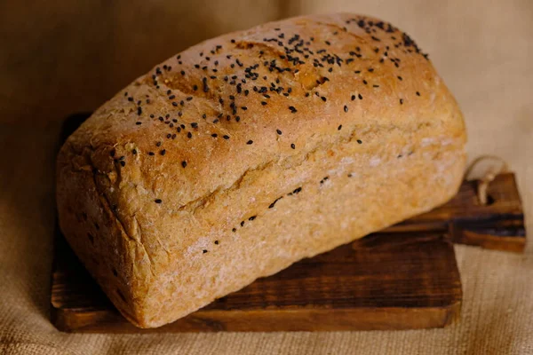 Pełnoziarnisty Chleb Zakwaśny Drewnianym Stole Posypać Czarnym Sezamem Powierzchni Chleba — Zdjęcie stockowe