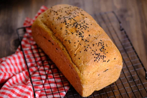 Whole wheat bread topped with black sesame. made from whole wheat baked in the oven. served on a cooling rack on a white marble table. country multigrain bread.