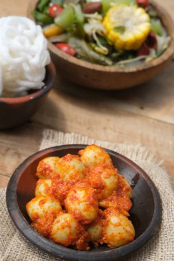 Telur Balado Tomatı ya da geleneksel Endonezya usulü yumurta, haşlanmış yumurta, domates ve biber ezmesi ya da sambal ile yapılan geleneksel Endonezya yemeği, ahşap masadaki toprak tabağında servis edilir. Sarımsak, domates, biber..