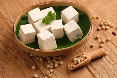 Tofu ya da soya peyniri geleneksel soya fasulyesinden yapılan yemektir. Bambu kabında dilimlenmiş tofu ve muz yaprağı. tahu putih. Tahta masa. Tahta kaşık.