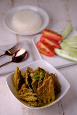 Tengkleng Kambing, baharatlar, soya sosu ve biberli, genç keçi kemiklerinden yapılan geleneksel bir Orta Cava yemeğidir. Kahverengi ahşap bir masada beyaz bir seramik kasede servis ediliyor. Endonezya yemekleri.