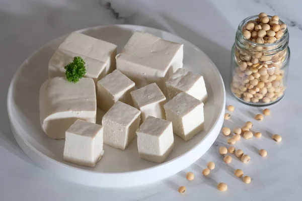 stock image tofu or bean curd is traditional food made from soybeans. sliced tofu at white ceramic plate. Tahu Putih. Soybeans in the glass jar.