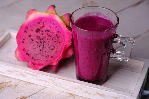 red dragon fruit smoothie. red dragon fruit juice. A healthy drink made from dragon fruit, high in vitamin C and antioxidants. diet drinks that are beneficial to health. served on white wooden table.