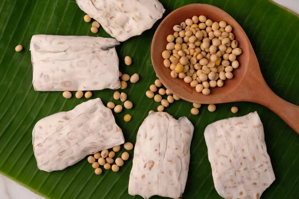 stock image Raw tempeh or tempe. tempeh slices in bamboo woven container. raw soybean seeds on a wooden table. Tempe is a traditional Indonesian food made from fermented soybeans.