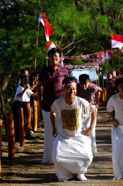 Yogya, Endonezya. 13 Ağustos 2023. Endonezya Cumhuriyeti Bağımsızlık Günü anısına plajda kırmızı ve beyaz bayrak taşıyan Endonezyalı gençler. Bendera Merah Putih. 