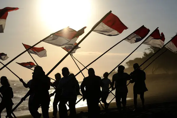 stock image Yogya, Indonesia. August 13, 2023. Indonesian youth carrying the Red and White flag on the beach to commemorate the Independence Day of the Republic of Indonesia. Bendera Merah Putih. 