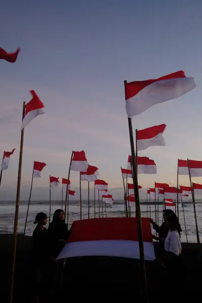 stock image Yogya, Indonesia. August 13, 2023. Indonesian youth carrying the Red and White flag on the beach to commemorate the Independence Day of the Republic of Indonesia. Bendera Merah Putih. 