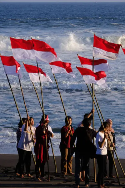 stock image Yogya, Indonesia. August 13, 2023. Indonesian youth carrying the Red and White flag on the beach to commemorate the Independence Day of the Republic of Indonesia. Bendera Merah Putih. 