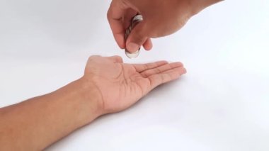 Beyaz arka planda diğer ele bozuk para vermek için yakın plan. Bin rupia sikke..