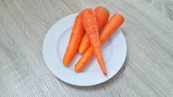 新鲜的胡萝卜放在木制桌子上的白盘上 新鲜蔬菜 — 图库照片