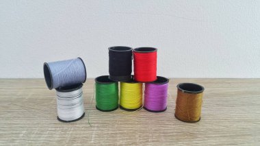 Ahşap masa üzerinde beyaz arkaplan ile renkli dikiş ipliği makaraları