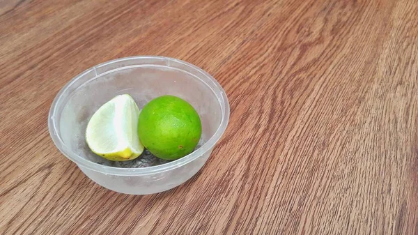 Limefrukter Plastskål Träbordet — Stockfoto