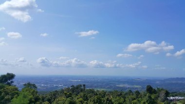 Dağlı güzel bir manzara ve beyaz bulutlu mavi bir gökyüzü. Yeşil ağaçlar.