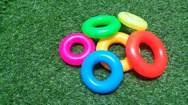 Pile of colorful plastic toy rings on artificial green grass
