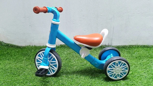 Синій Дитячий Триколісний Велосипед Штучній Зеленій Траві Білим Фоном Стіни — стокове фото