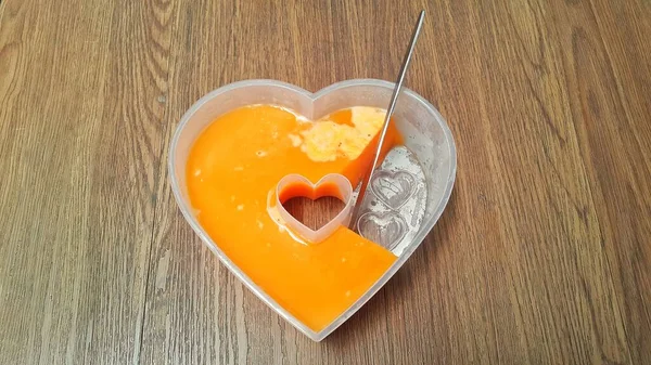 Sliced heart-shaped mango jelly on wooden background. A knife on a jelly mold plate.
