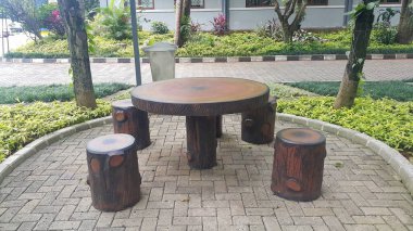 Taş masa ve bahçede ahşap desenli banklar.