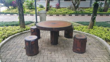 Taş masa ve bahçede ahşap desenli banklar.