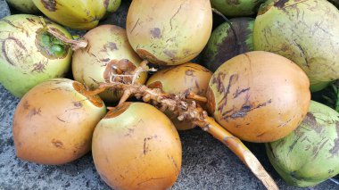 Beton zeminde portakal ve yeşil hindistan cevizi yığını.