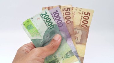 El ele tutuşan rupiah parası beyaz arka planda izole edilmiş. Endonezya Rupisi.
