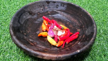 Kil tabakta acı biber sosu yapmak için gerekli malzemeleri kapat. Kırmızı biber, soğan ve tuz. Kaval ve taş havanda soğan ve kırmızı biber. Yemek malzemesi. Yapay yeşil çimen.