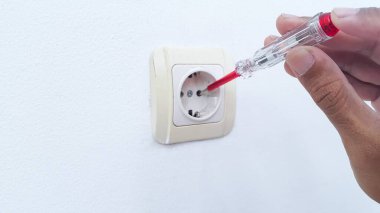 Handyman repair wall outlet at home. Worker using voltage electric tester to check outlet. Electrician service concept.