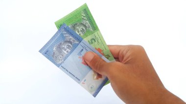 Hand holding Malaysian Ringgit money on white background. One and five Malaysian ringgit banknotes.