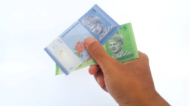 Hand holding Malaysian Ringgit money on white background. One and five Malaysian ringgit banknotes.