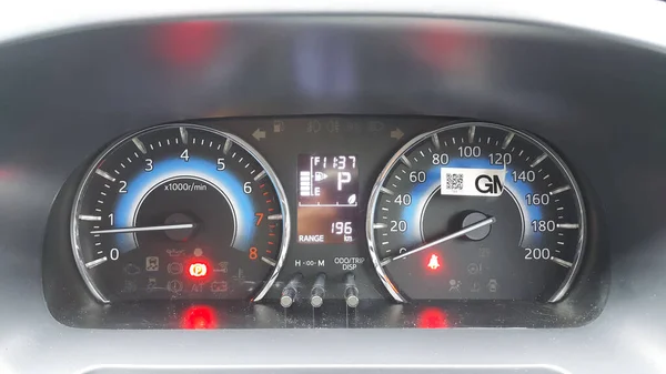 Close-up of a car panel with a speedometer with brake and seat belt light indicators on