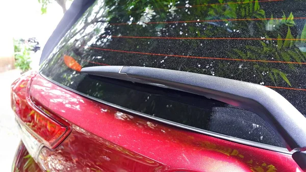 Close up of rear wiper in red car. Car rear window with anti fog. Outdoors.