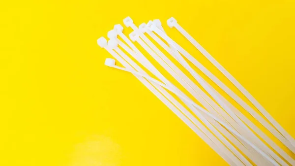 White plastic cable ties isolated on yellow background