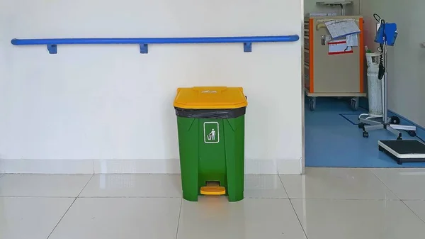 Closed trash can on the floor and wall with handrail for elderly or disabled people in a hospital. Handrail for elderly care facility.