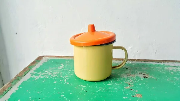 Żółty Puchar Pomarańczową Pokrywą Zielonym Drewnianym Stole — Zdjęcie stockowe